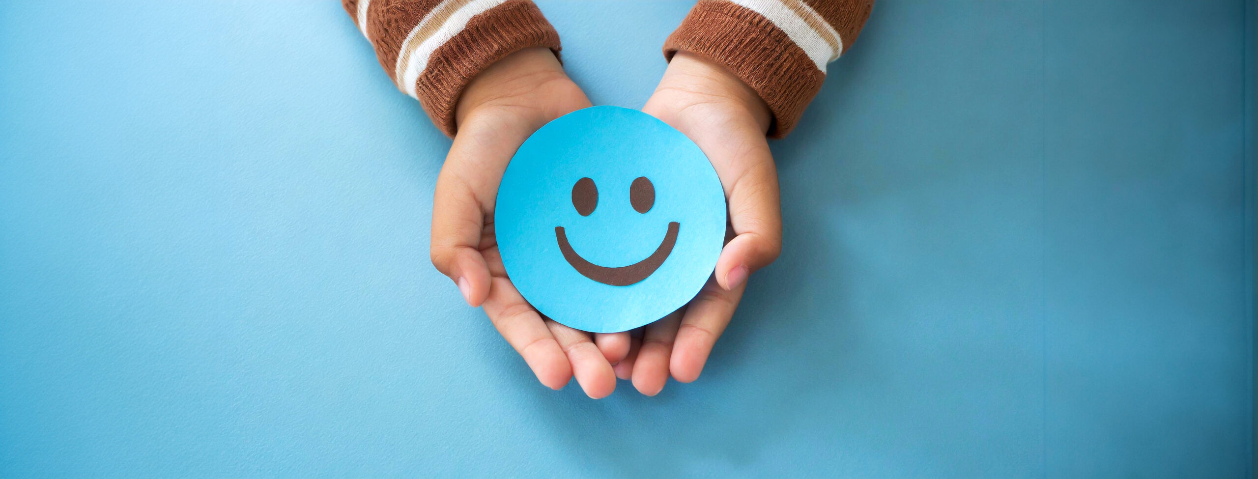 dental plan to make you smile Hands of a Child Holding a Smiley Face Made of Blue Paper